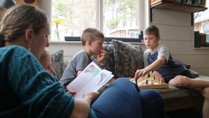 mom reading while kids play chess